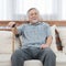 Portrait of senior old elderly asian man sit on coach hand hold help walking stick sit on sofa in house look at camera with