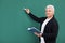 Portrait of senior teacher with book and chalk at green board