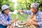 Portrait of senior winemaker holding in his hand a glass of new white wine. Smiling happy elderly couple enjoying a picnic