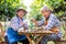 Portrait of senior winemaker holding in his hand a glass of new white wine. Smiling happy elderly couple enjoying a picnic