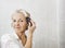 Portrait of senior woman brushing hair in bathroom