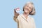 Portrait of senior woman holding an election badge against blue background