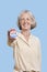 Portrait of senior woman holding an election badge against blue background