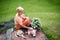 Portrait of senior woman with pet dog sitting outdoors in garden, relaxing with coffee.