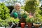 Portrait Of Senior Woman Potting Plant In Garden At Home