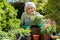 Portrait Of Senior Woman Potting Plant In Garden At Home