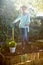 Portrait of senior woman standing with garden fork and shovel on dirt