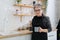 Portrait of a senior woman with two cups in her hands on the background of the kitchen, preparing a morning hot drink