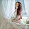 Portrait of sensual curly haired girl in a white dress against t