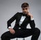Portrait of sensual pensive young man in tuxedo sitting