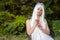 Portrait of Sensual Relaxed Caucasian Bride with Tiara and Long White Hair Posing In The Green Garden Outdoors