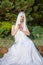 Portrait of Sensual Relaxed Caucasian Bride with Tiara and Long White Hair Posing In The Green Garden Outdoors