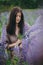 Portrait of sensual stylish woman in rustic dress holding lupine bouquet in meadow. Cottagecore aesthetics. Young female in linen