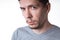 Portrait of a sensual young model in unlabeled gray t-shirt posing on white background. Serious man with small beard close-up