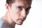 Portrait of a sensual young model in unlabeled gray t-shirt posing on white background. Serious man with small beard close-up