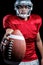 Portrait of serious American football player showing ball