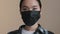 Portrait serious Asian girl sick woman indoors putting on face protective black medical mask protecting health from