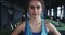 Portrait of serious beautiful young determined female athlete looking at camera, sweaty after exercising at local gym.
