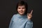 Portrait of Serious boy showing index finger. Studio shot, gray background. Human emotions, facial expression concept