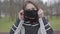 Portrait of serious brunette Caucasian girl putting on face mask and looking aroung outdoors. Young pretty woman