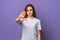 Portrait of serious brunette girl showing stop taboo sign, extending hand palm to prevent something, prohibit action, purple