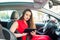 Portrait of serious business lady, caucasian young woman driver in red summer suit setting up the route on a navigator while