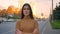 Portrait of serious caucasian brunette watching modestly into camera with her arms crossed on road background.