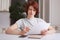 Portrait of serious concentrated red haired female with short hairstyle, looks attentively into documents, surrounded with modern