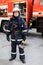 Portrait of serious and confident caucasian fireman standing and holding hammer, wearing special protective uniform in the truck