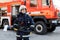 Portrait of serious and confident caucasian fireman standing and holding hammer, wearing special protective uniform in the truck