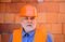 Portrait of serious construction worker in safety vest and helmet. Bearded architect builder in protective hard hat on