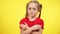 Portrait of serious cute little girl with pigtails and crossed hands looking at camera shaking head no. Unhappy