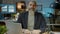 Portrait of serious entrepreneur in formal clothing sitting at desk in dark office