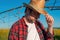 Portrait of serious farmer standing in front of center-pivot irrigation equipment in rapeseed field