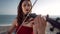 Portrait of serious female musician playing violin enjoying sound standing in sunshine on Mediterranean sea shore