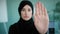 Portrait serious frustrated angry Arabian Muslim Islamic girl in black hijab upset woman looking at camera holding hand