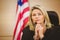 Portrait of a serious judge with american flag behind her