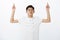 Portrait of serious-looking charming young chinese male student in white t-shirt raising hands, pointing and looking up