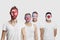 Portrait of serious Multi-ethnic group of male friends with various national flags painted on their faces standing against white b