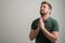 Portrait of serious stylish attractive man with thick beard, dressed in casual green t shirt is praying