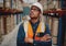 Portrait of serious supervisor in warehouse standing with folded hands looking high at shelves with material while