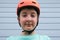 Portrait of a serious teen caucasian boy wearing orange sport crash helmet, learning to ride bicycle or skateboard in