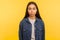 Portrait of serious unsmiling brunette girl in denim shirt standing calm, looking focused concentrated at camera