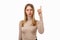 Portrait of Serious young blond woman showing index finger. Girl raises finger up  says: Attention please