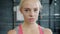 Portrait of serious young sportswoman in sports clothing looking at camera in gym