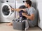Portrait of sexy man with dirty clothes near washing machine. man sits in front of washing machine. Dirty