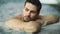 Portrait of sexy man enjoying in whirlpool bath. Handsome guy relaxing in pool