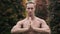 Portrait of shirtless man with muscular body doing yoga exercises in garden