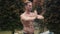 Portrait of shirtless man with muscular body doing yoga exercises in garden