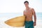 Portrait of shirtless muscular man holding surfboard at beach